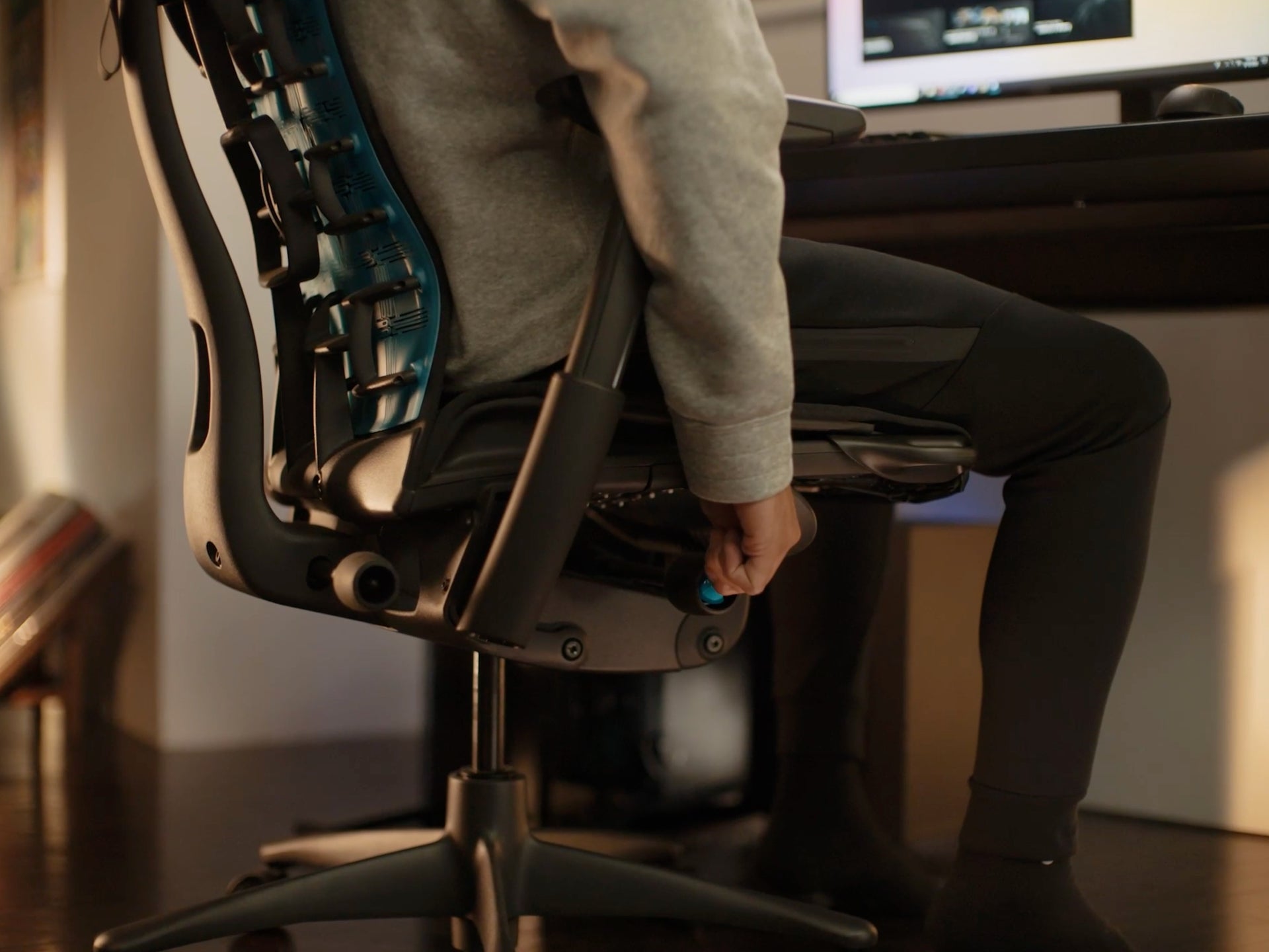 特写图片：Embody电竞椅的侧面，一个人正在调整座椅高度机制。