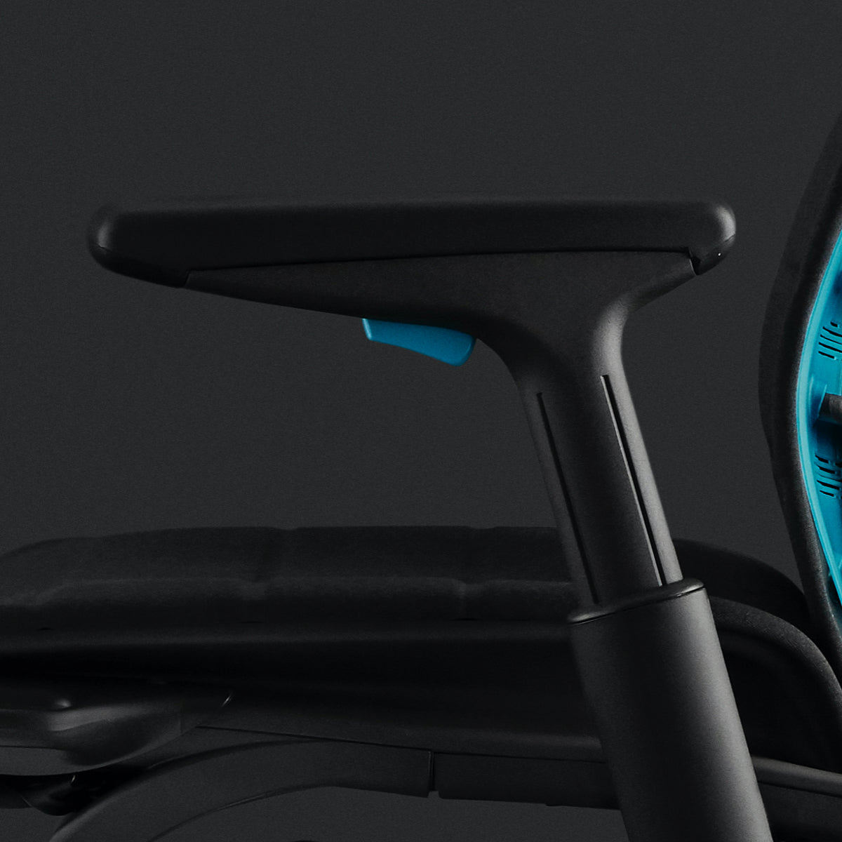 Embody电竞椅左侧扶手上的黑色注塑泡沫特写。同时也展示了黑色背景中座椅上的青蓝色调整器和青蓝色靠背。