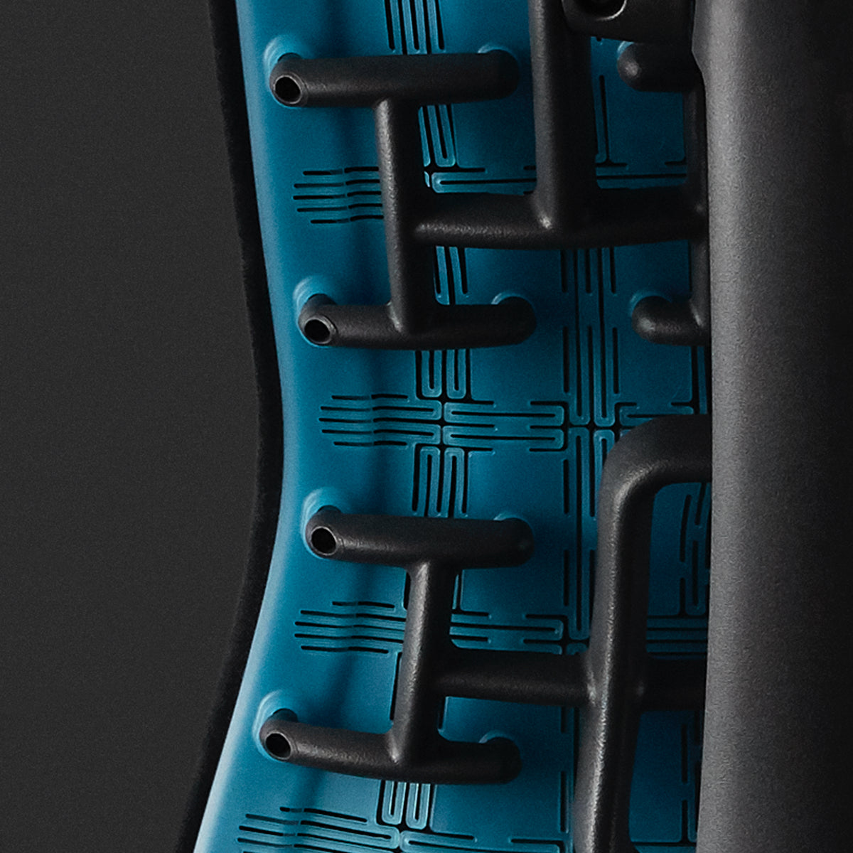 黑色背景中Embody电竞椅上的青蓝色磨砂靠背和支柱特写。