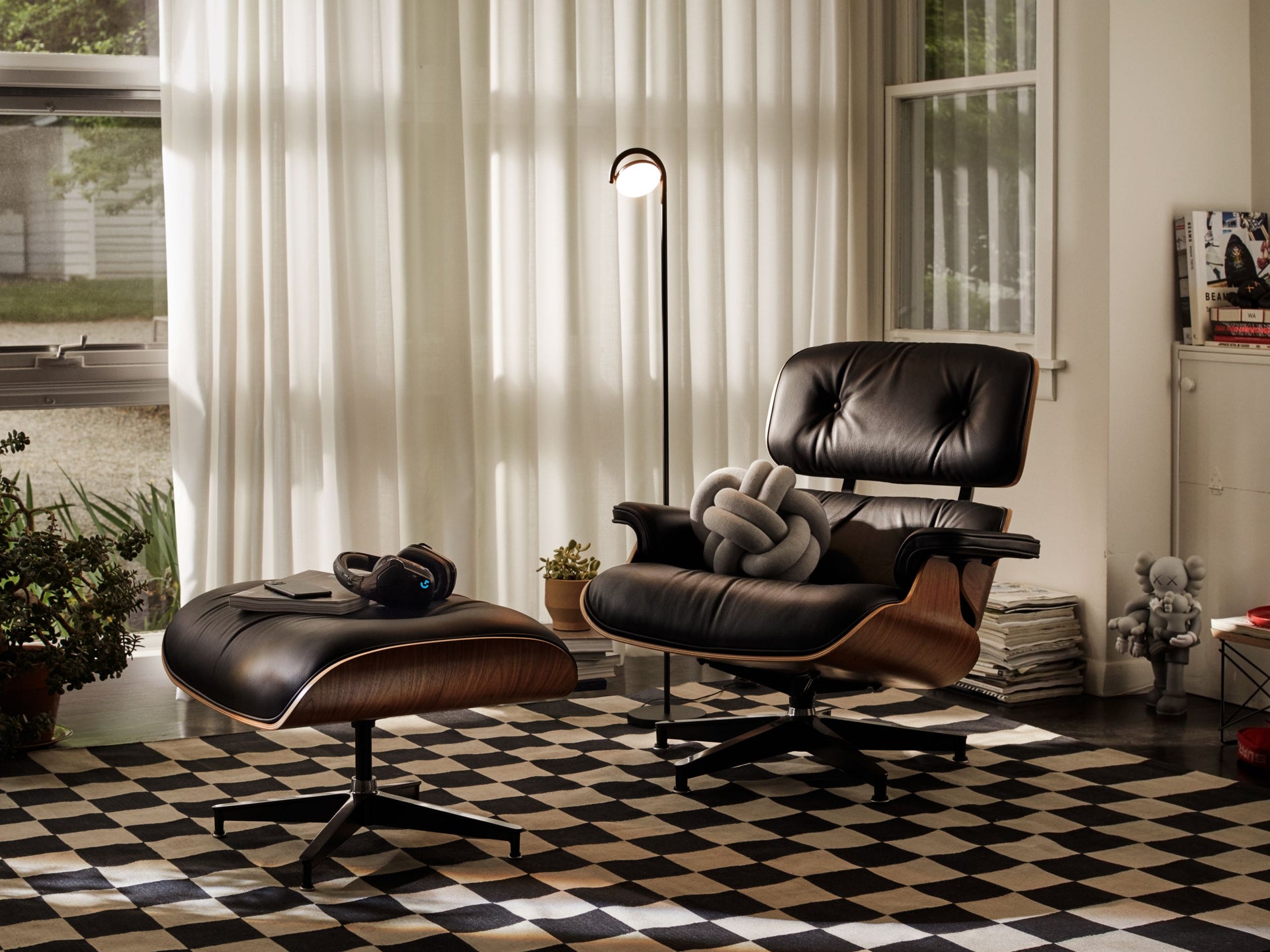 格子地毯上摆放着一张黑色皮革的Eames躺椅。