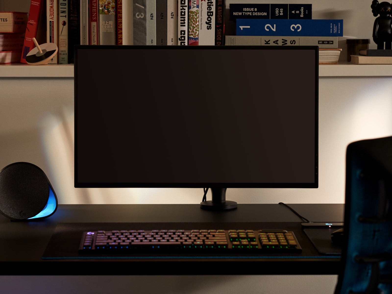 桌上的挂臂连接着一台大型显示器，表示Ollin显示器挂臂可以容纳所有尺寸的屏幕，显示器前面有一个键盘，背后的架子上摆放着各种物品。